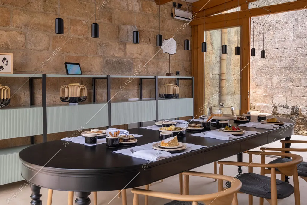 Grande sala da pranzo con lampadario di design e pareti in roccia a vista