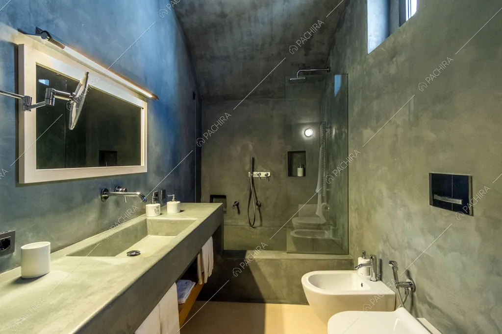 Bagno con sanitari sospesi, pareti délabré e grande box doccia con vasca
