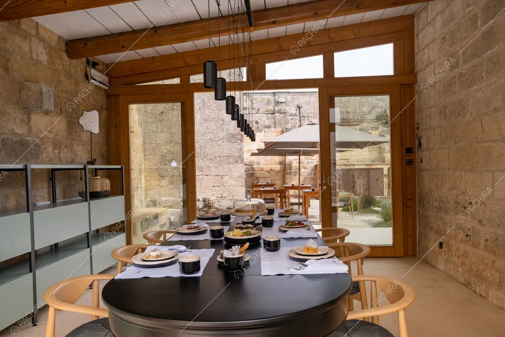 Sala da pranzo con pareti in roccia a vista e porte-finestre per accedere al giardino