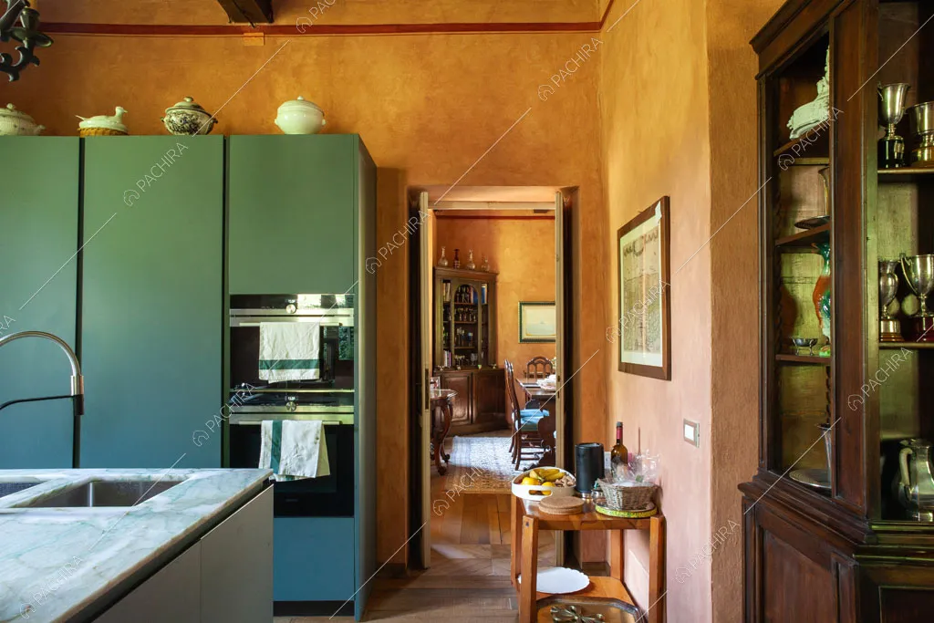 Cucina con isola dal piano in marmo, credenza antica e pareti rosate