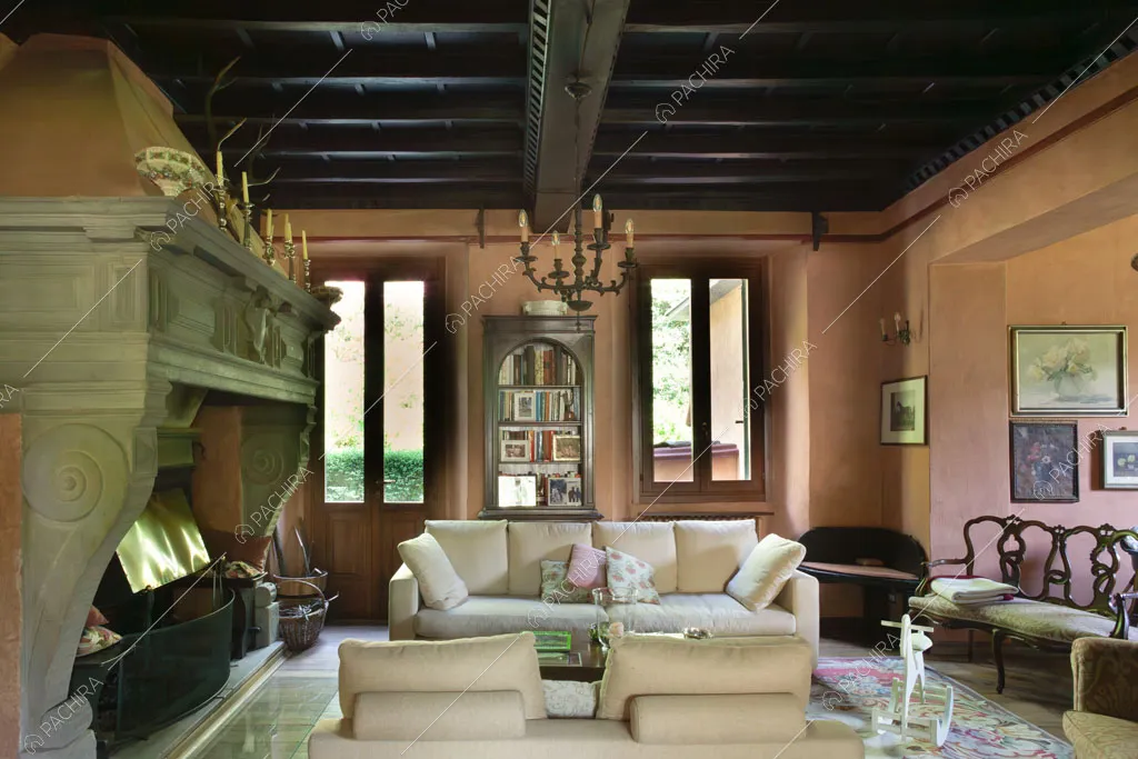 Soffitto in cassettoni nella sala con pareti rosate e grande camino con boiserie
