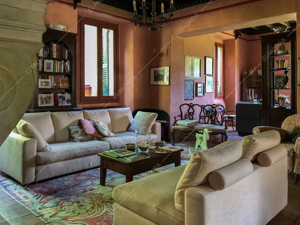 Divani nella luminosa sala con pavimento in parquet e lampadario antico