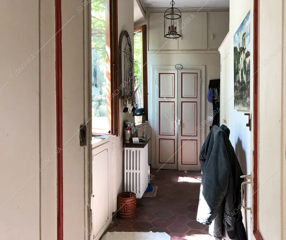 Corridoio con pareti bianche e vista sulla porta con boiserie