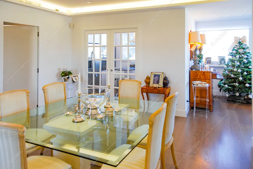 Tavolo da pranzo con piano in cristallo e scorcio sulla cucina tramite la porta a vetri