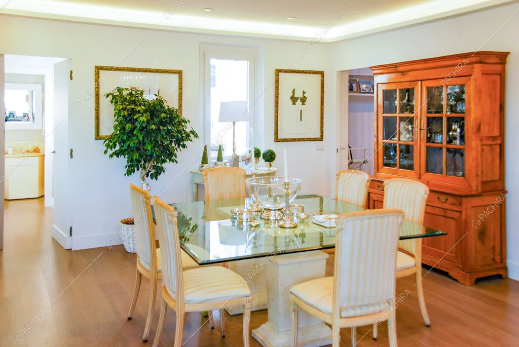 Tavolo da pranzo nella luminosa sala con pavimento in parquet e credenza antica