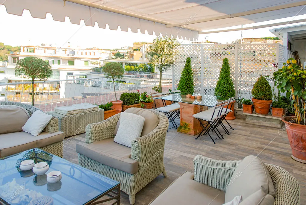 Poltrone in vimini sulla terrazza con tavolo da pranzo e pavimento in parquet