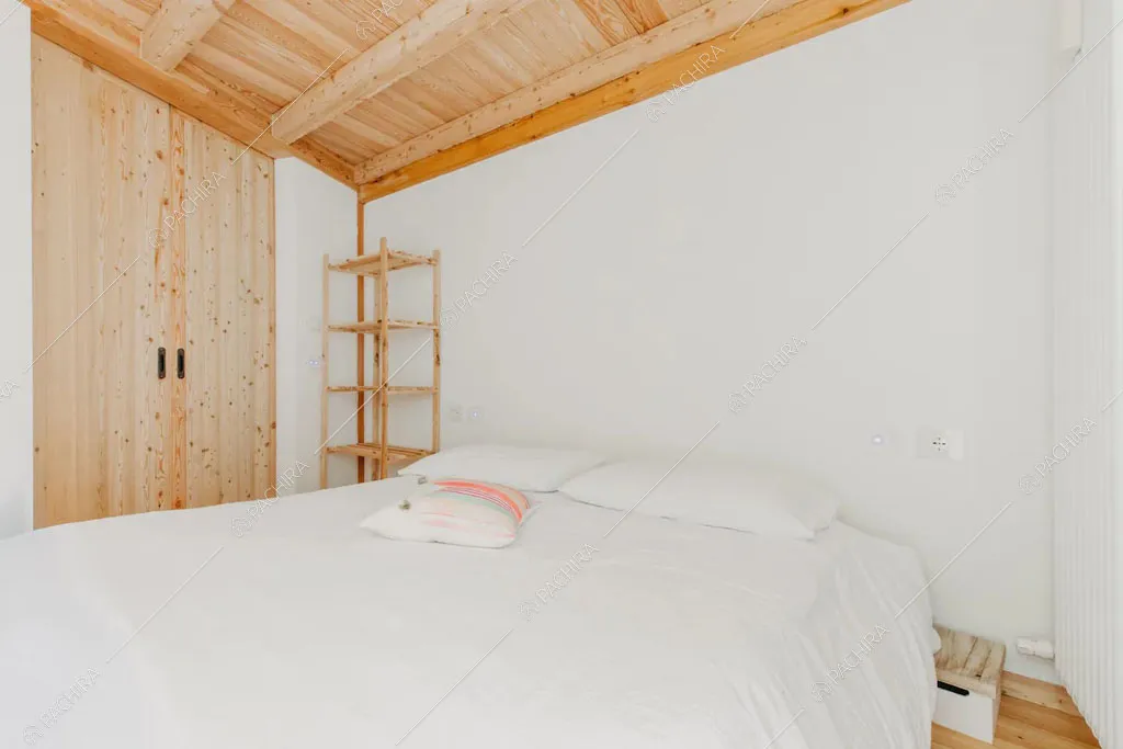Travi a vista sul soffitto della camera da letto matrimoniale dello chalet Timor, location in stile rustico a Trento