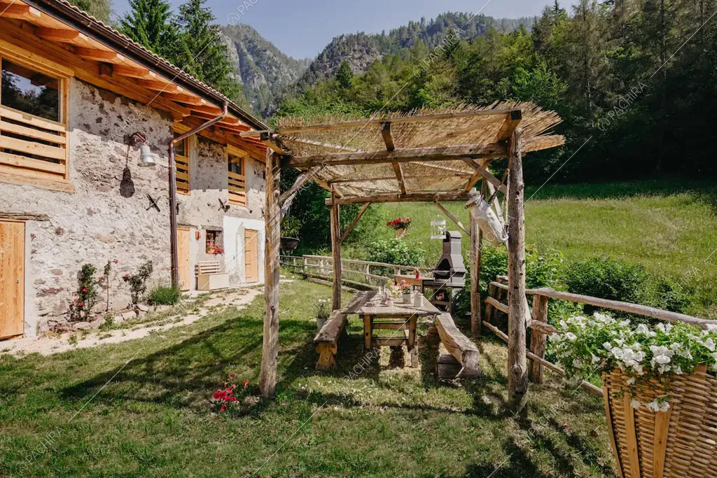 Veranda con tavolo da pranzo nel giardino dello chalet Timor, location in stile rustico a Trento