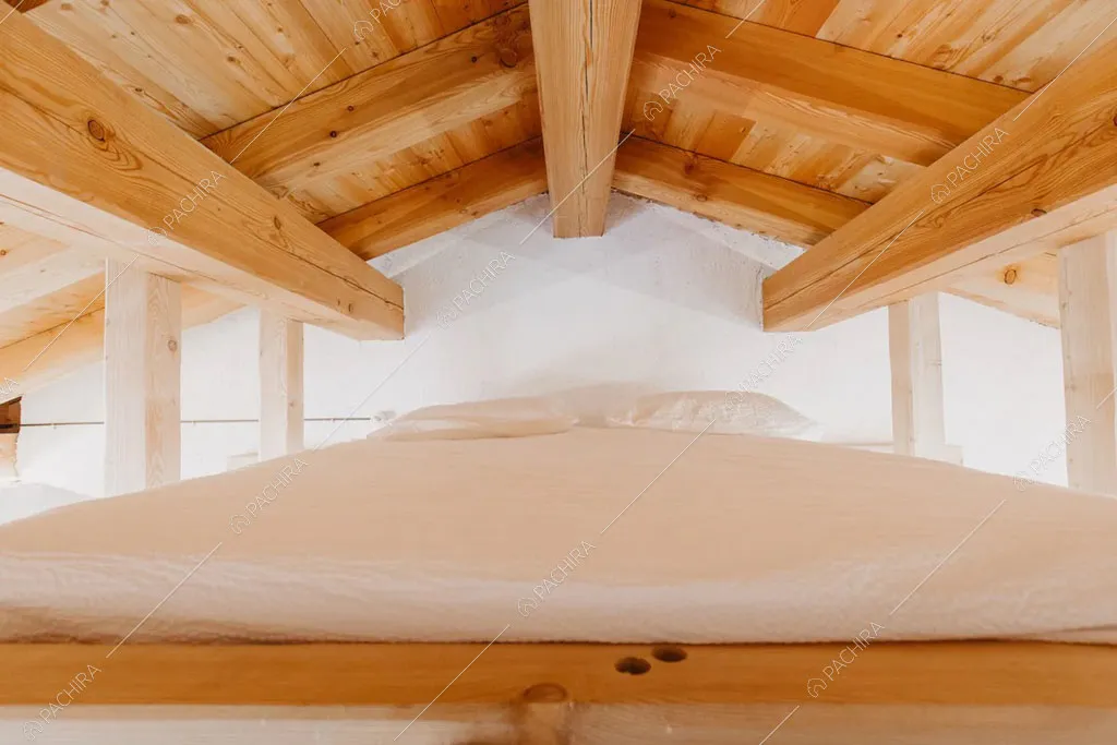 Letto matrimoniale sul soppalco dello chalet Timor, location in stile rustico a Trento