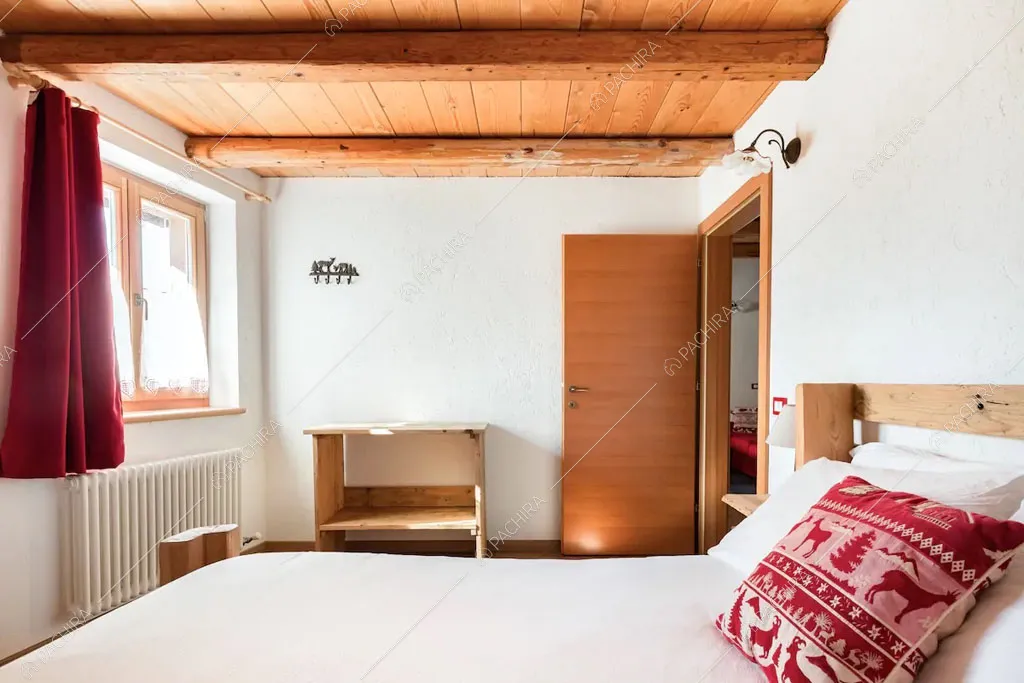 Pareti bianche della camera da letto dello chalet Cantabrico, location in stile rustico a Trento