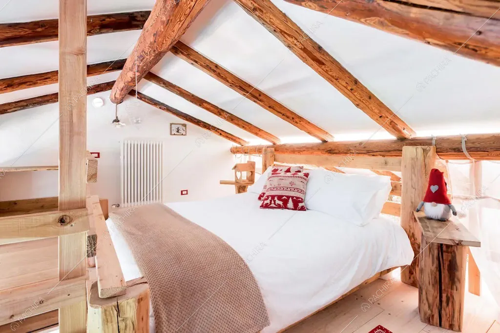 Camera da letto matrimoniale con pavimento in parquet dello chalet Cantabrico, location in stile rustico a Trento