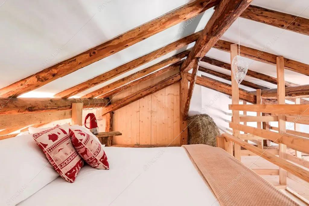 Travi in legno a vista sul soffitto della camera da letto dello chalet Cantabrico, location in stile rustico a Trento