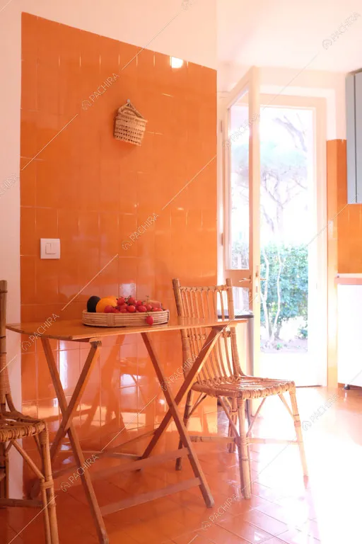 Sala da pranzo con parete arancione della villa Larzac, location in stile moderno a Livorno