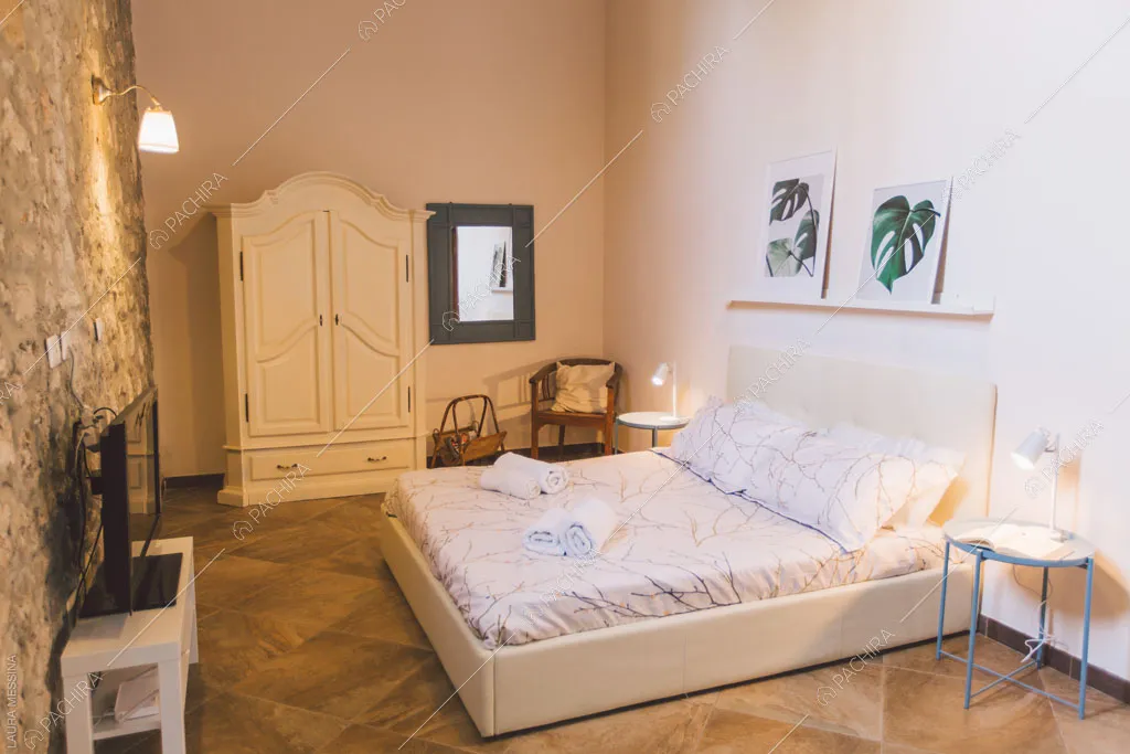 Parete in pietra a vista della camera da letto della villa Hibiki, location in stile moderno a Siracusa