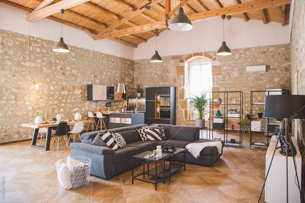 Zona living con pareti in pietra a vista della villa Hibiki, location in stile moderno a Siracusa