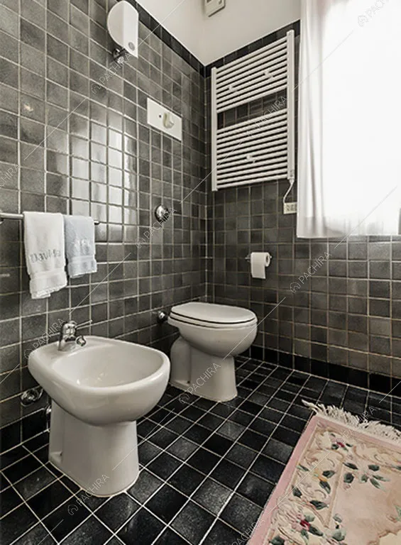 Piastrelle nere su pavimento e pareti del bagno dello chalet Betel, location in stile rustico a Lecco