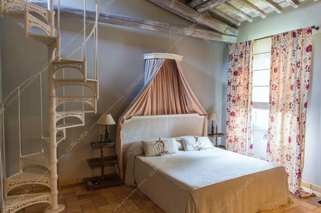 Camera da letto con travi in legno a vista sul soffitto della villa Pieris, location in stile rustico a Roma