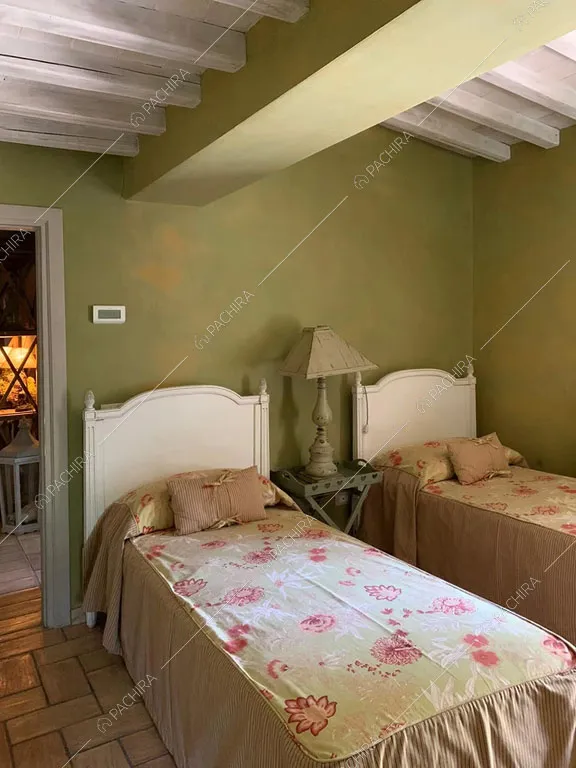 Letti singoli nella camera con pareti verdi della villa Pieris, location in stile rustico a Roma
