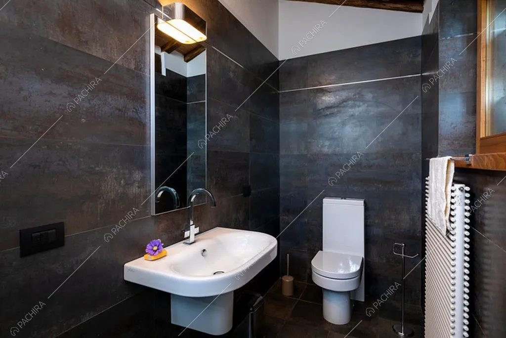 Bagno con pareti e pavimento in piastrelle nere della villa Bardenas, location in stile rustico a Siena