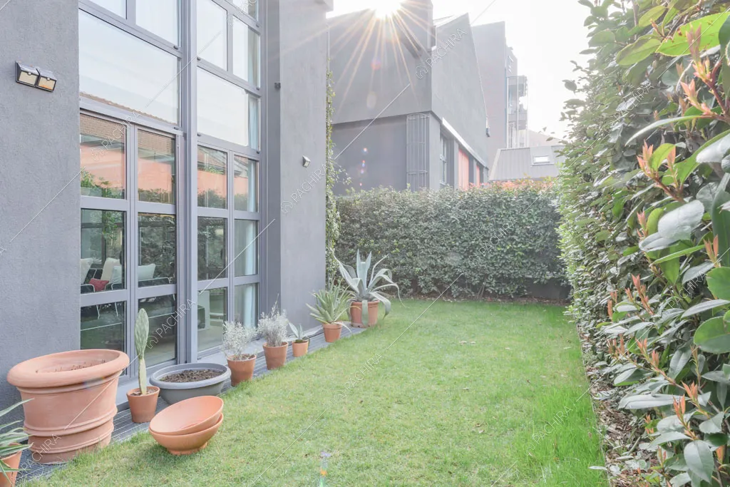 Giardino con vista sugli esterni grigi del loft Crisopazio, location in stile contemporaneo a Milano