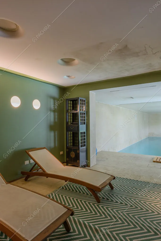 Lettini, pareti verdi e vista sulla piscina interna della location