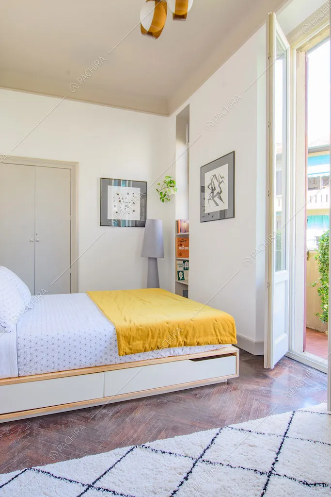 Luminosa camera da letto matrimoniale con pavimento in parquet a spina di pesce