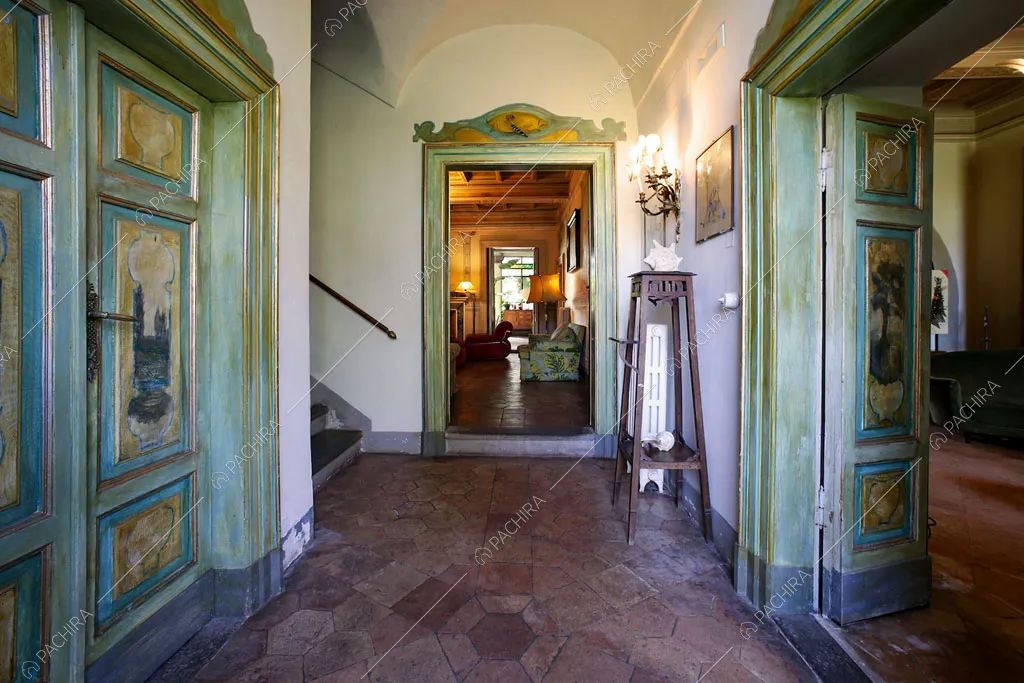 Atrio con pareti bianche, soffitto a volta a botte e vista sulle porte affrescate e dalle nuances verdi