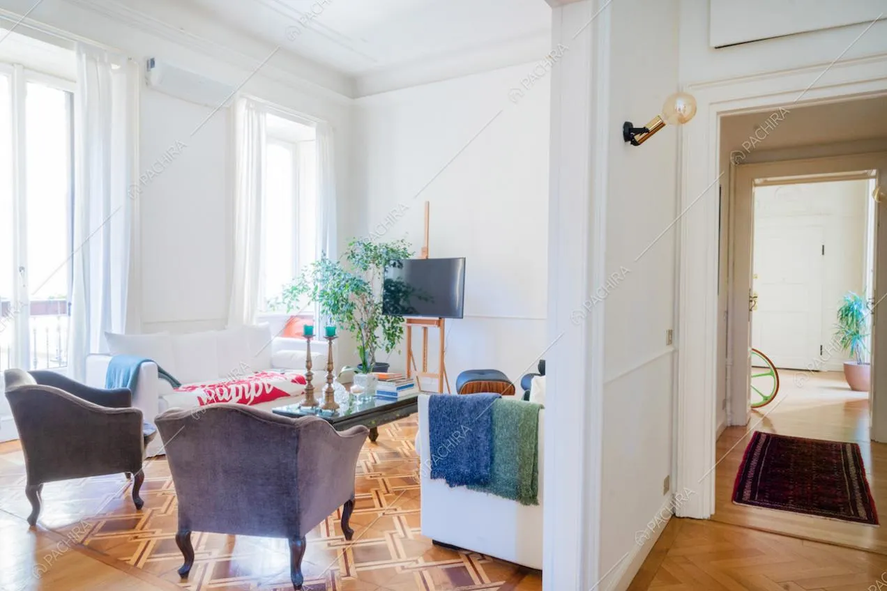 Vista sul salotto con pavimento in parquet e sul corridoio con boiserie alle pareti