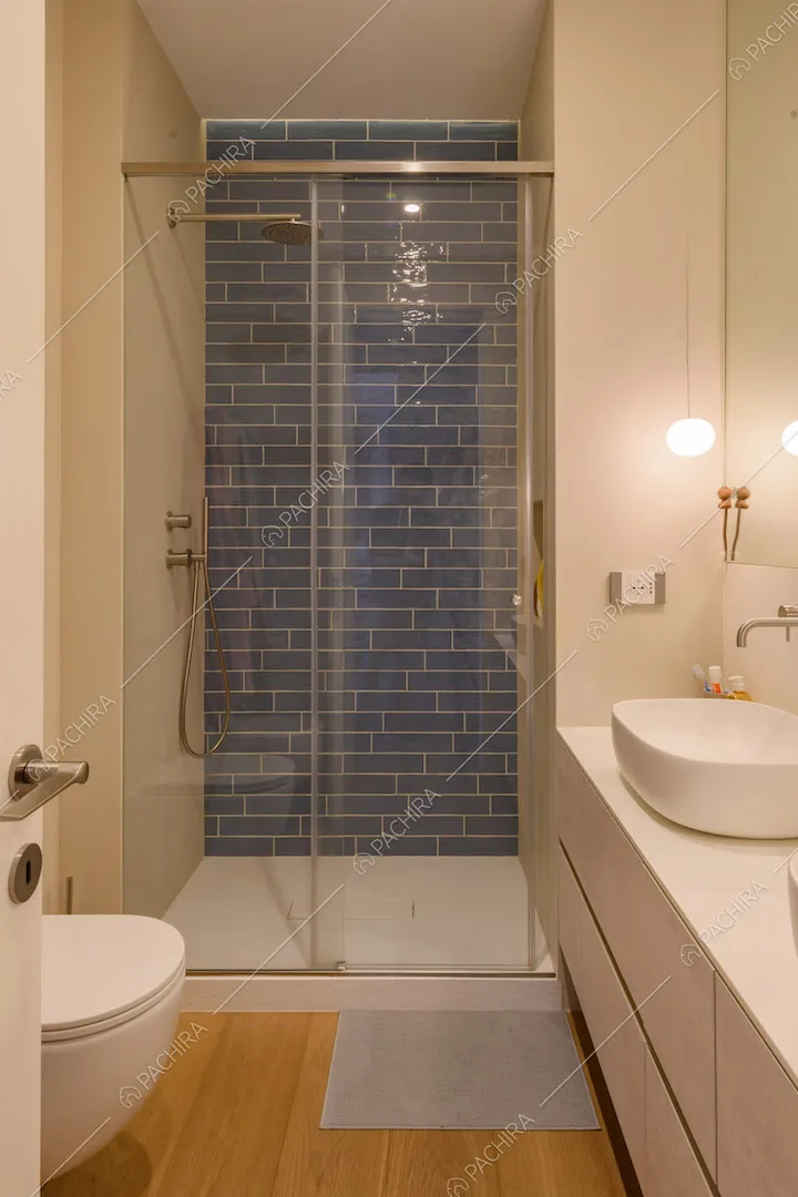 Bagno con pavimento in parquet e parete in mattoni blu nel box doccia