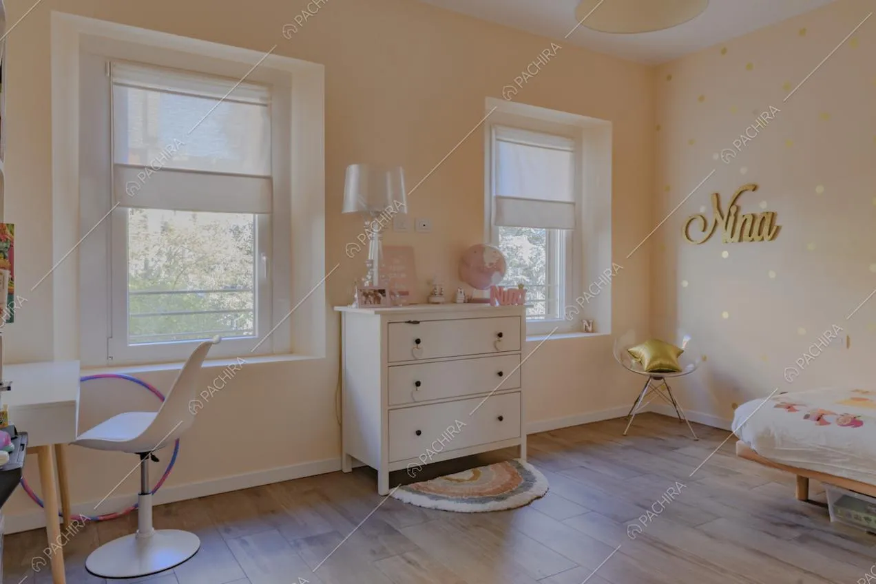 Pavimento in parquet, cassettiera e finestre nella cameretta