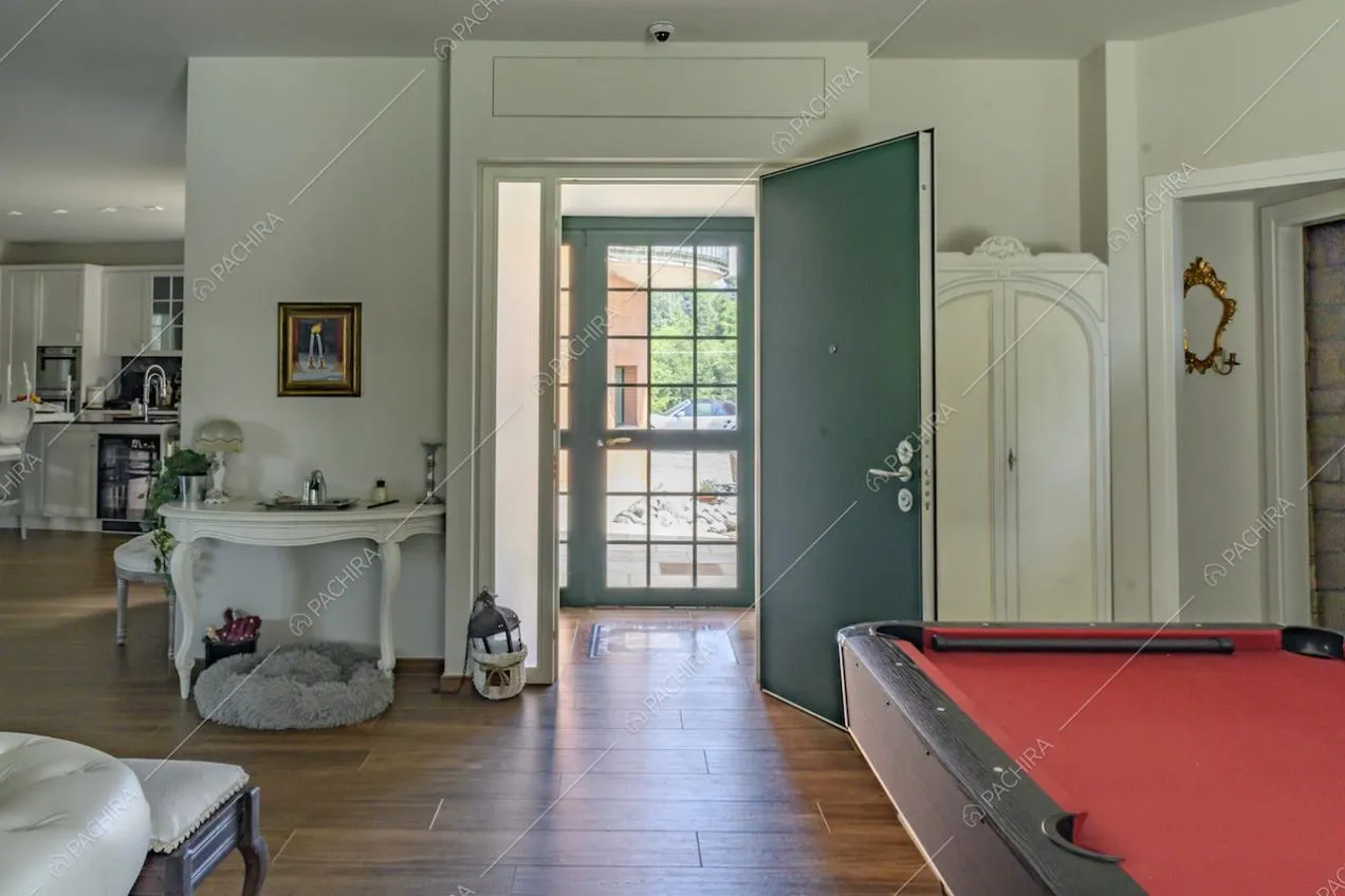 Dal soggiorno, dalle pareti bianche e pavimento in parquet, vista sulla porta d'ingresso verde