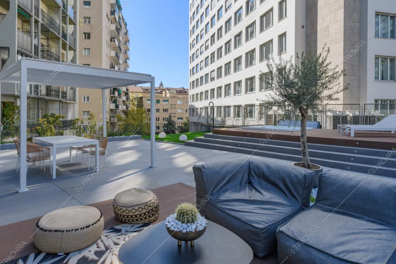 Divano grigio sulla terrazza con gazebo bianco e vasca idromassaggio