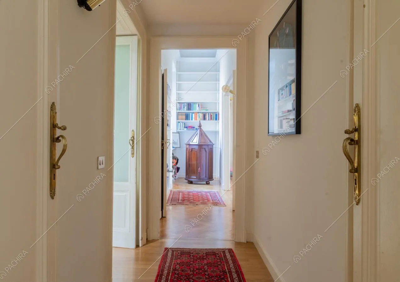 Corridoio con pavimento in parquet, pareti bianche e vista sulla camera da letto