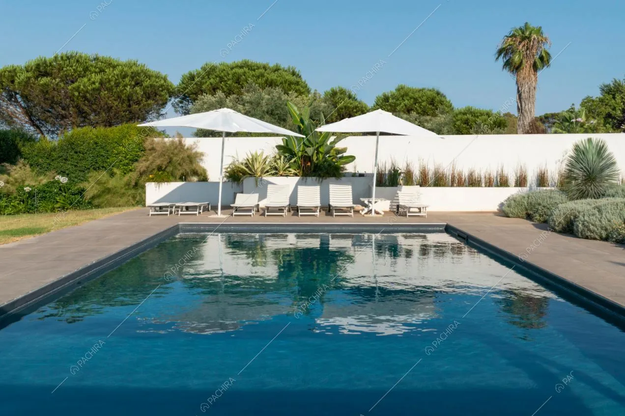 Piscina nel giardino con lettini e ombrelloni bianchi