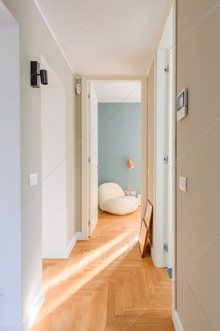 Lungo corridoio con pareti beige e pavimento in parquet a spina di pesce italiana