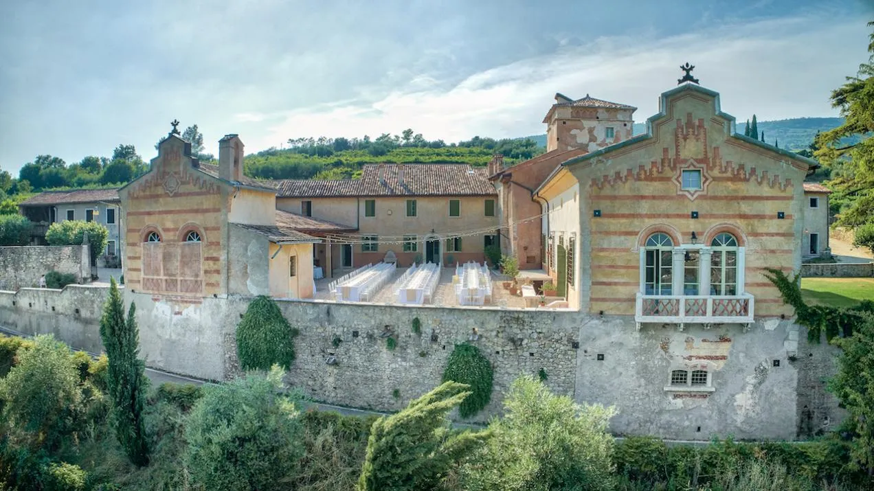 Dall'alto vista sulla location cinta da mura, con esterni affrescati gialli e rossi e ampia corte