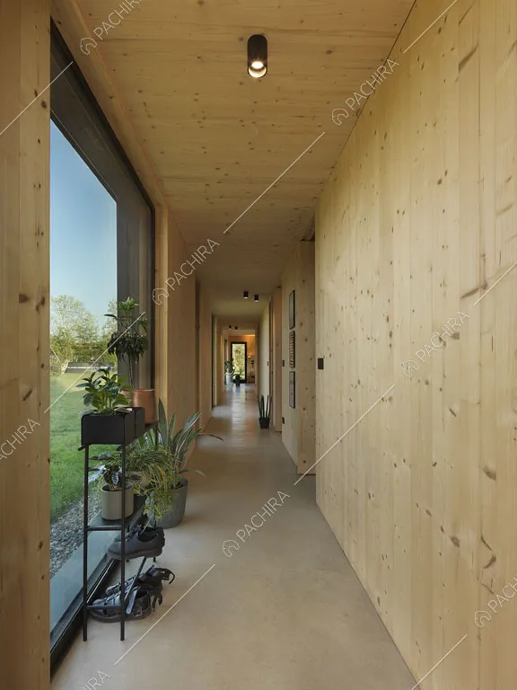 Lungo corridoio con faretti sul soffitto in legno e grandi vetrate