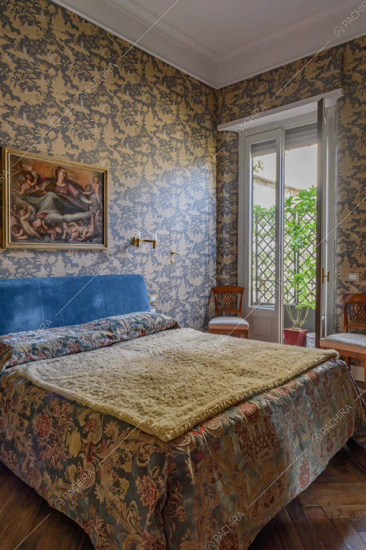 Camera da letto matrimoniale con boiserie sul soffitto, carta da parati e porta-finestra per accedere alla terrazza
