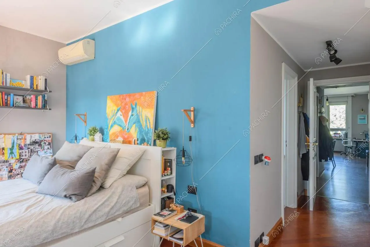 Camera da letto con parete azzurra e pavimento in parquet