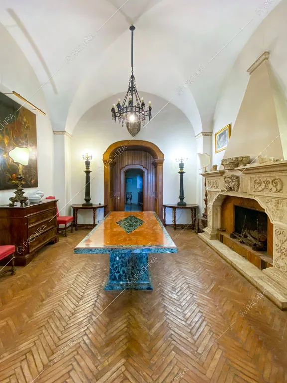 Sala con pavimento in parquet a spina di pesce, lampadario antico e grande camino in marmo