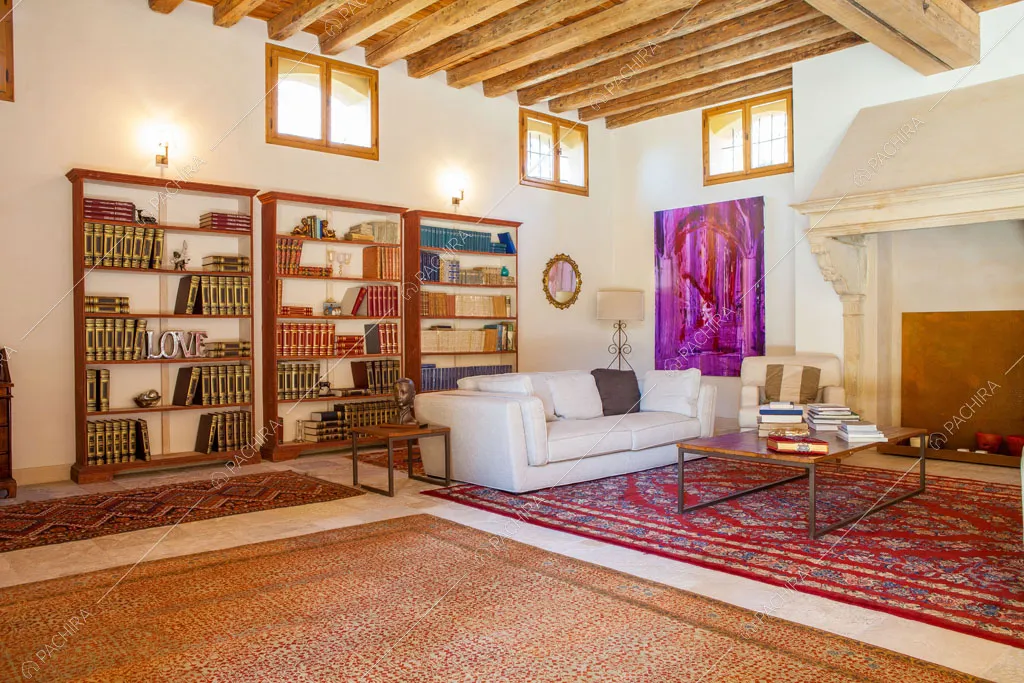 Zona living con travi in legno a vista sul soffitto, pareti bianche e grande camino