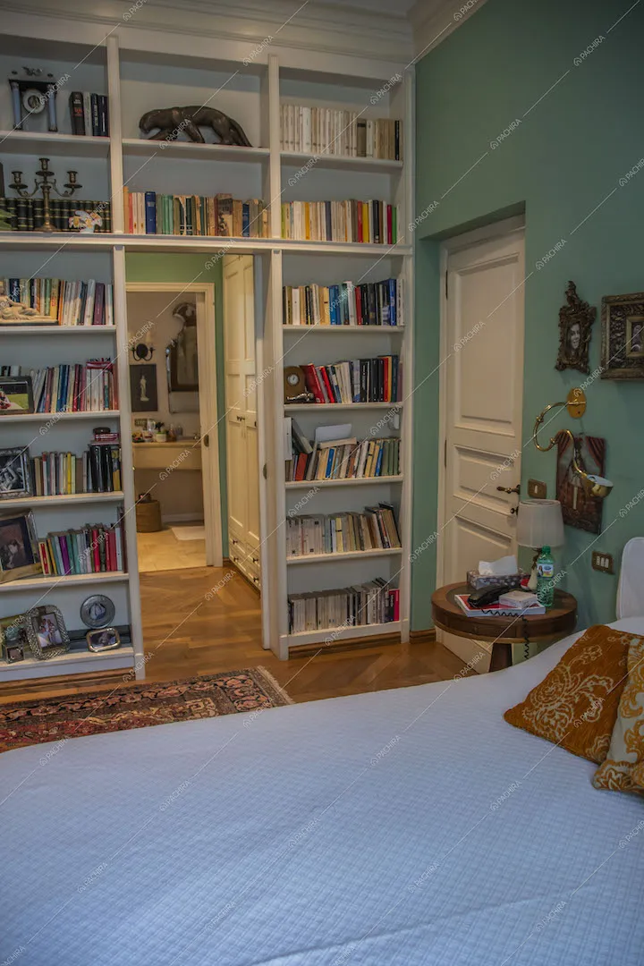 Letto matrimoniale nella camera con libreria a muro e vista sul bagno