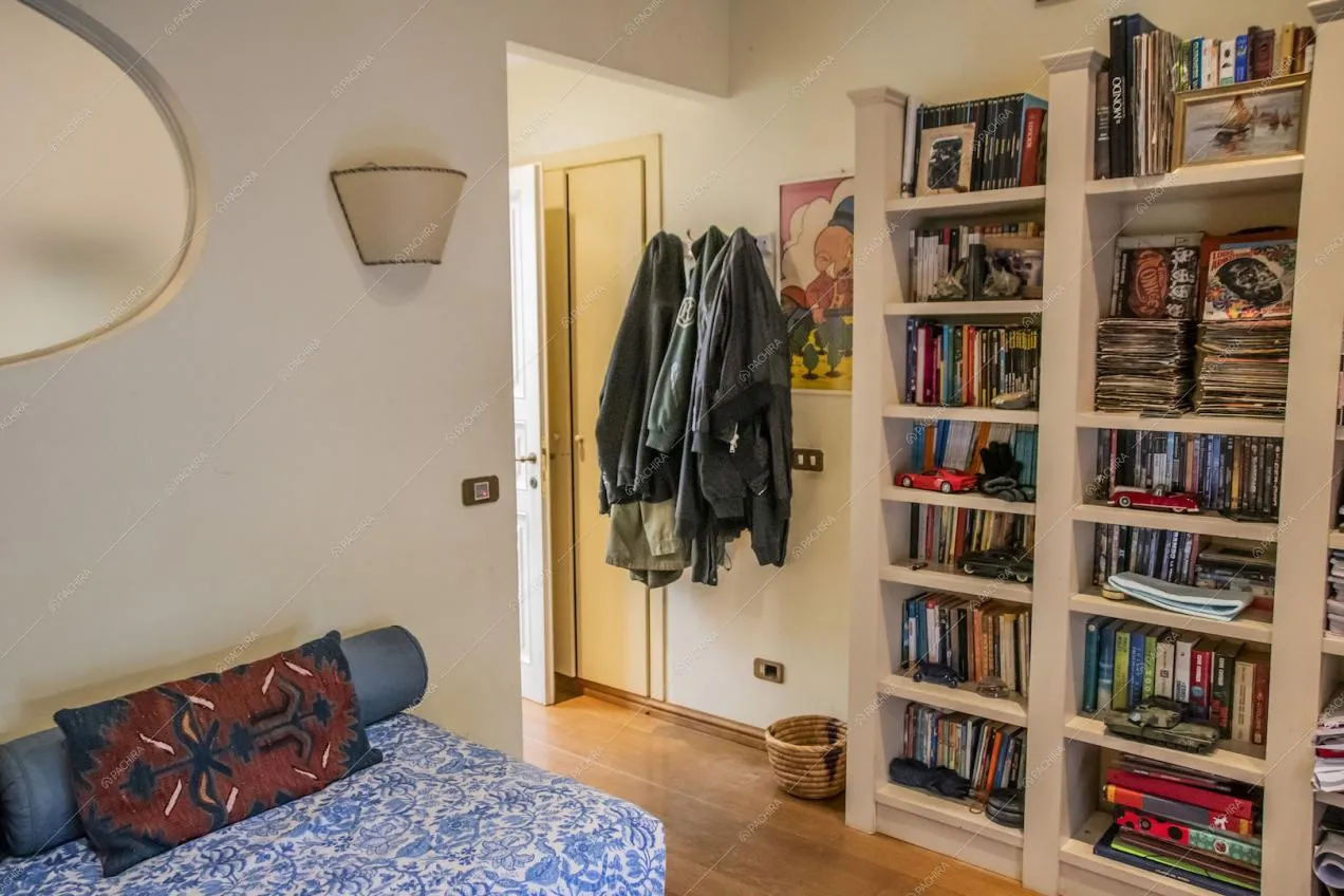 Camera dalle pareti bianche con pavimento in parquet e libreria bianca