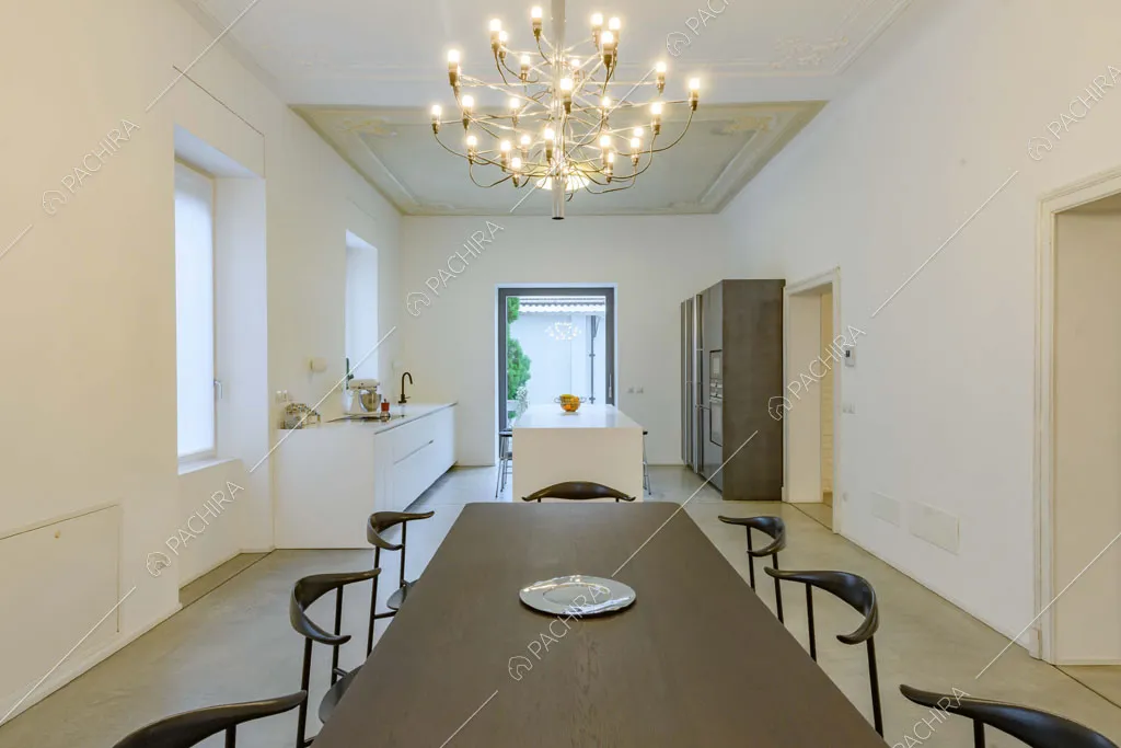 Dal tavolo da pranzo nero vista sulla cucina con isola e sul lampadario antico