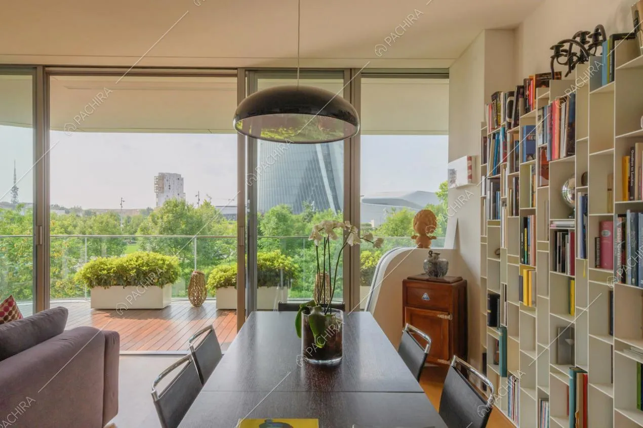 Luminosa zona living con libreria, tavolo da pranzo e porte-finestre scorrevoli