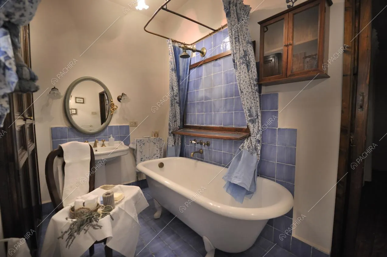 Vasca da bagno, piastrelle azzurre e specchio tondo con cornice
