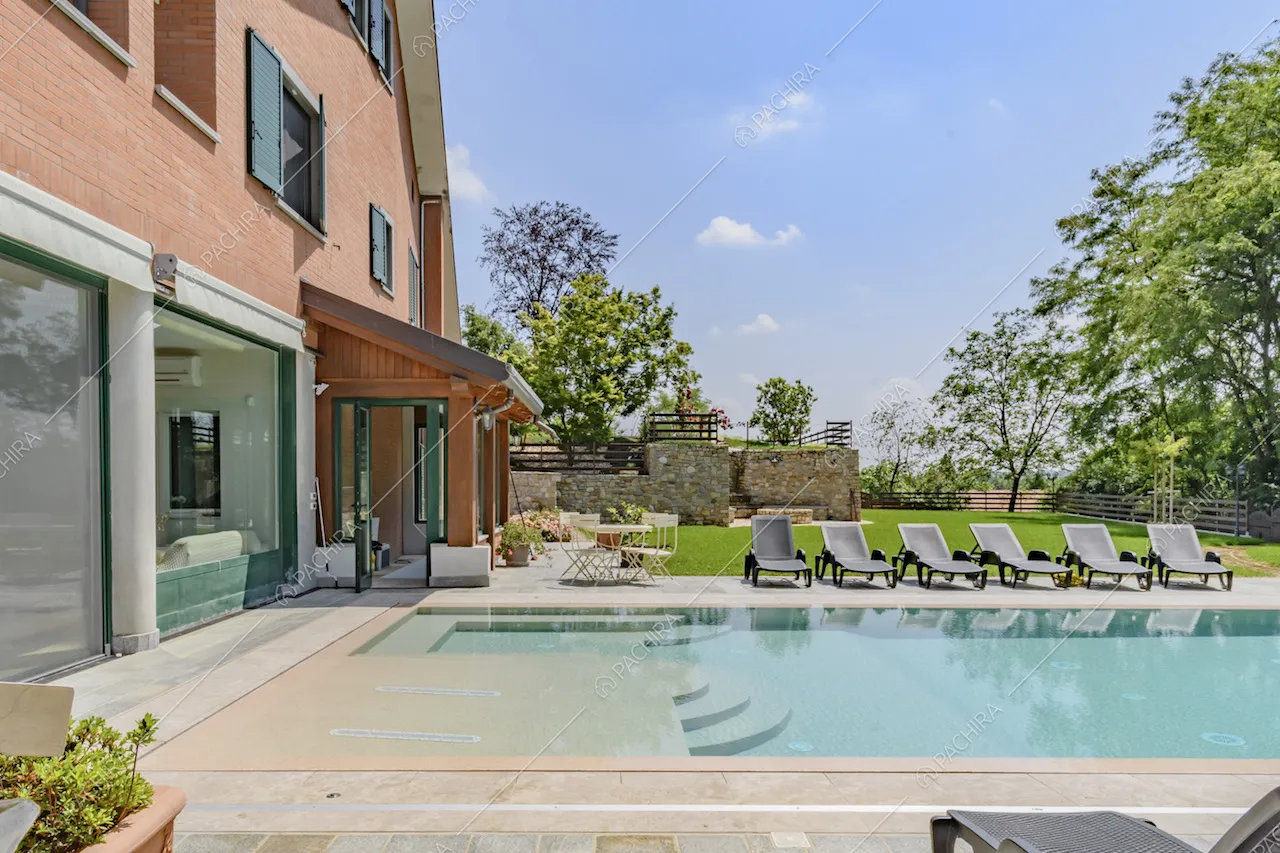 Piscina a sfioro della location, con lettini a bordo vasca e veranda dalle ampie vetrate