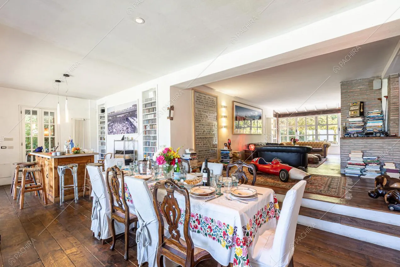 Tavolo da pranzo nella sala con pareti bianche e pavimento in parquet, collegato al salotto e alla cucina