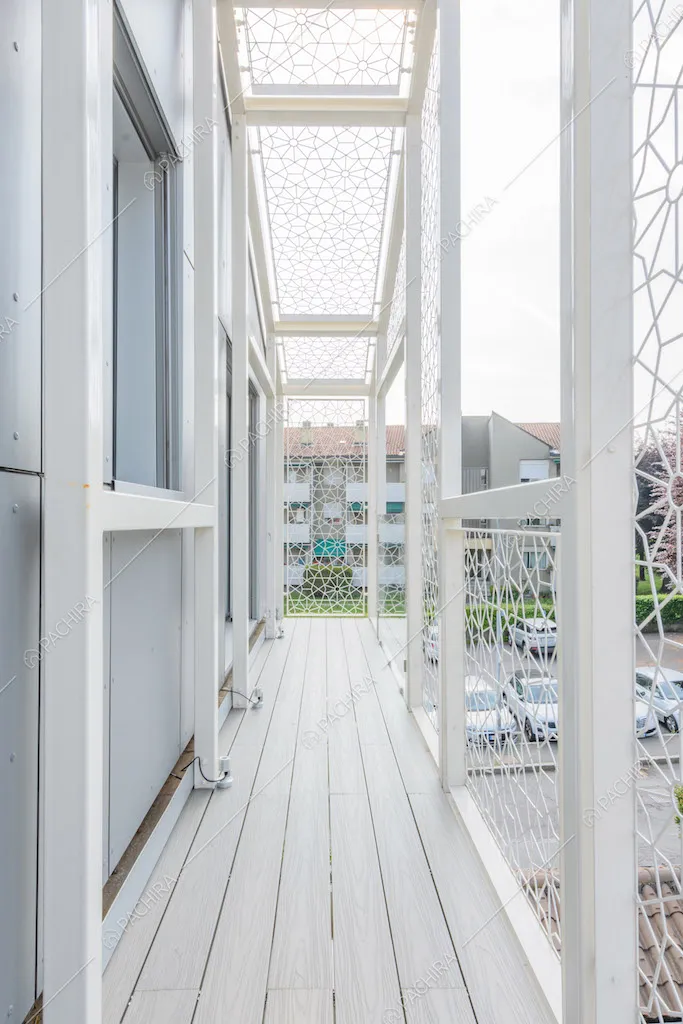 Lungo balcone con parapetto bianco e pavimento in parquet da esterni