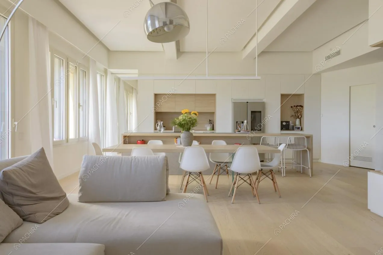 Open space con divano, tavolo da pranzo con sedie e cucina a vista